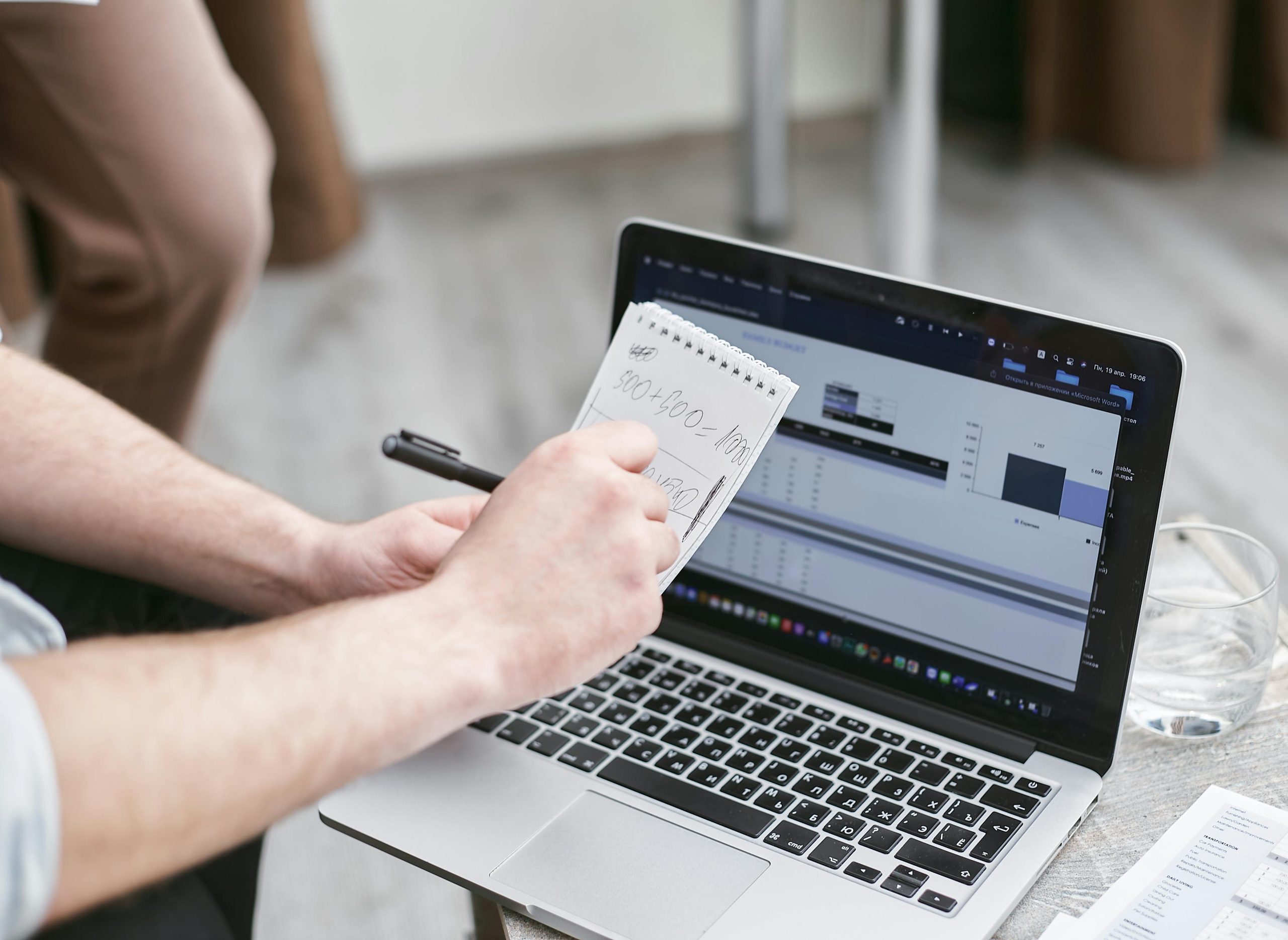 Person analyzing data on laptop while taking notes, focusing on market trends.
